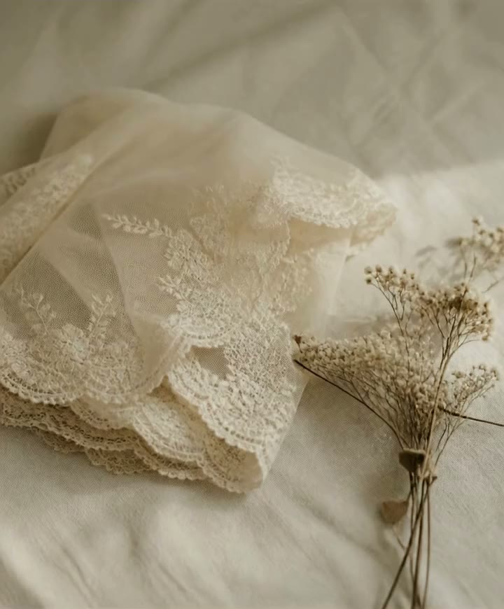 Ivory lace veil folded on cream linen with dried flowers
